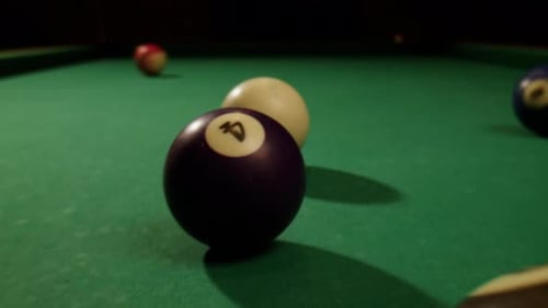 Jeune homme jouant au billard américain, poule, gros plan, boules colorées sur une table de billard verte