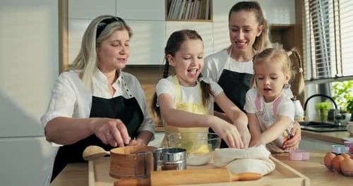 Glückliche Töchter mit Zöpfen Schwestern helfen Oma, Mehl vom Rücken zu nehmen, auf Sieb gießen