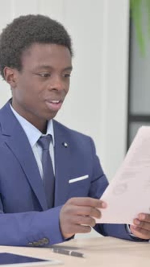 African Businessman Celebrating Success while Reading Documents in Office, Vertical Video
