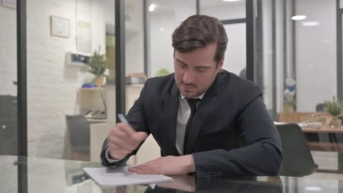 Man in Suit Writing at Office Desk