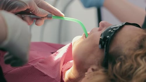 Dentist and His Assistant in Protective Masks Treat a Patient's Teeth in a Dental Clinic Healthcare