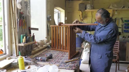 A Carpenter in the Workshop Assembling Furniture Parts in the Workshop in Natural Light