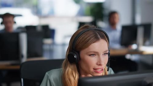 Help Desk Specialist Talking on Headset Working Computer at Office Closeup