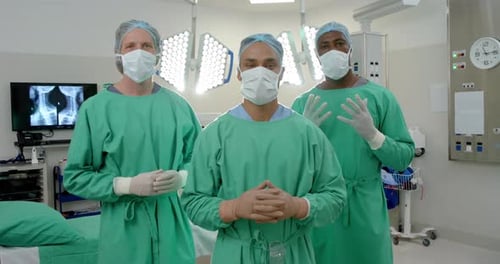 Portrait of diverse male surgeons wearing surgical gowns in operating theatre, slow motion