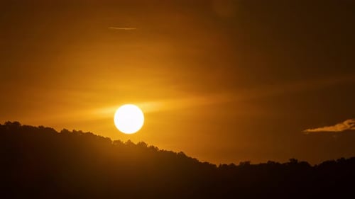 Timelapse of dramatic sunrise with orange sky in a sunny day.