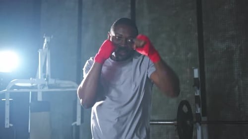 Fitness Workout in Gym African Man Fighter Preparing for Fight Punching with Red Boxing Wraps Sports
