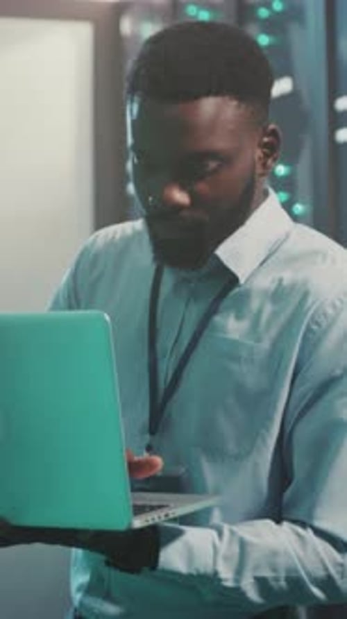 Man with Laptop in Data Center Inspecting Servers