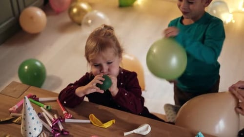 Child Blowing Up Balloon at Birthday Party