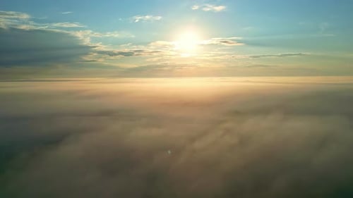 Soleil brillant haut dans le ciel au-dessus de la campagne recouverte d'un épais brouillard, vue aérienne