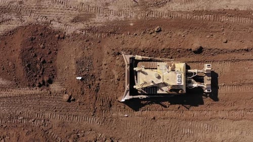 Bulldozer pushing large amount of fresh soil, Aerial follow footage.