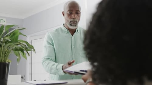 Man Handing Over Paperwork at Office Counter