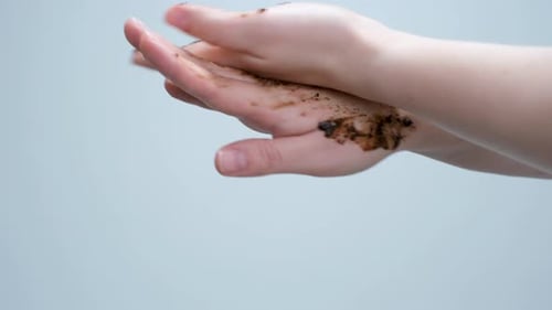Hands exfoliating with a brown scrub, close up