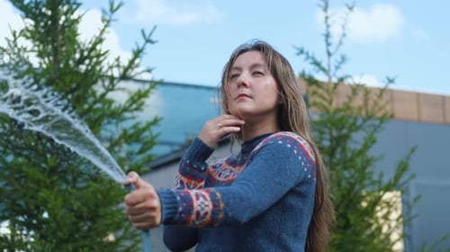 Woman Holding Garden Hose Between Green Pine Trees