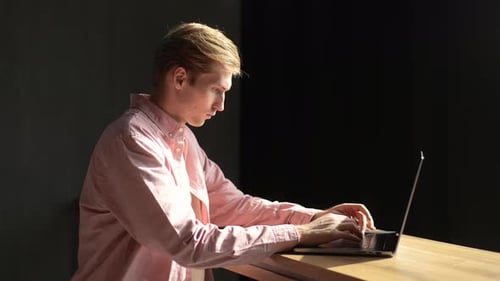 Side View of Serious Concentrated Male Freelancer Looking at Laptop Screen Working Remotely at Home