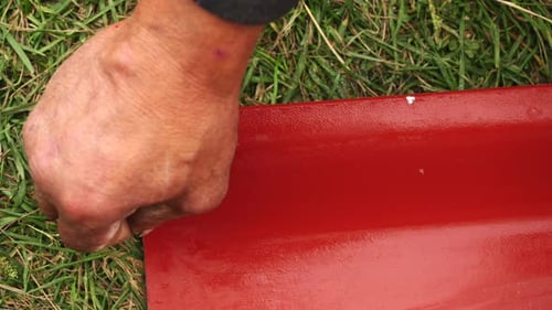 Construction Worker Snapping Chalk Line on Red Metal Roofing Sheet
