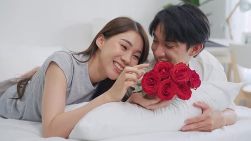 Young Couple Enjoying Roses on Bed