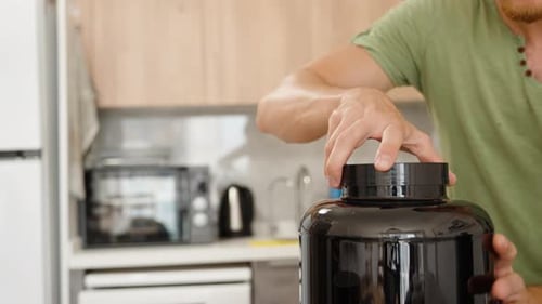 Man Opens Large Protein Jar in Kitchen