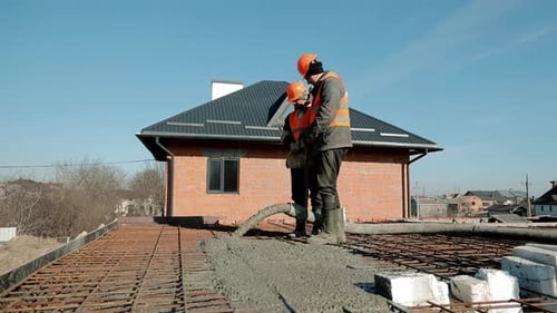 Bauarbeiter gießen mit Teamwork eine Betonplatte auf das Fundament des Betongitterbaus