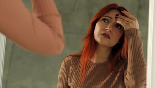 Woman Inspecting Face in the Mirror at Home