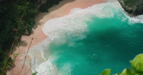 Tropischer Strand mit glattem rosafarbenem Sand und faszinierenden azurblauen Meereswellen, Blick von oben nach unten auf die wunderschöne