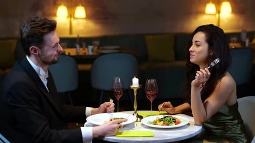 Happy Man and Woman Having Romantic Dinner in the Restaurant While Eating Salads and Toasting with