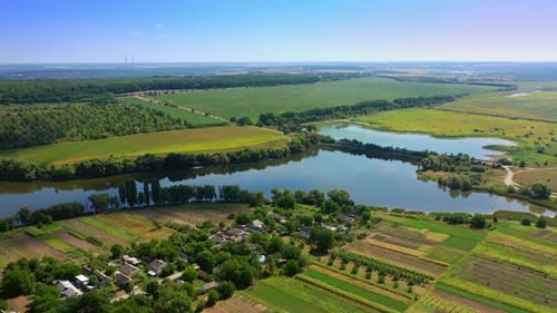 Little river floating in the green fields. Beautiful small village locating