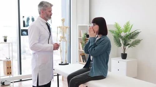 Family Physician Talking to Woman in Exam Room of Hospital