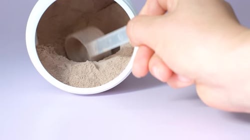Hand Scooping Protein Powder from Tub