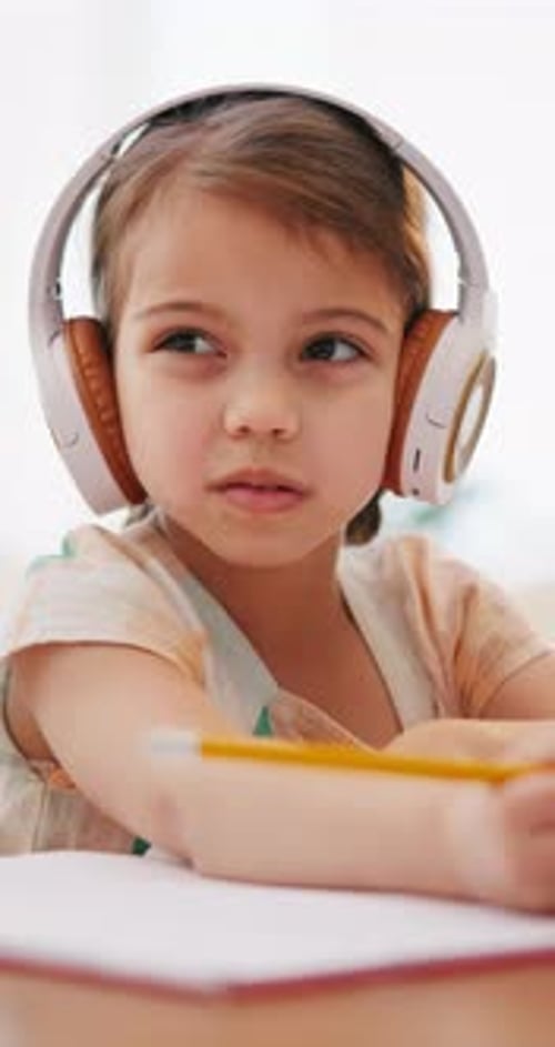 Writing, homework and child with headphones for education, online learning and studying in home