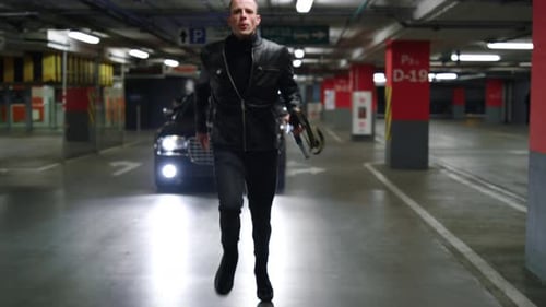 Man in leather jacket is running from police car