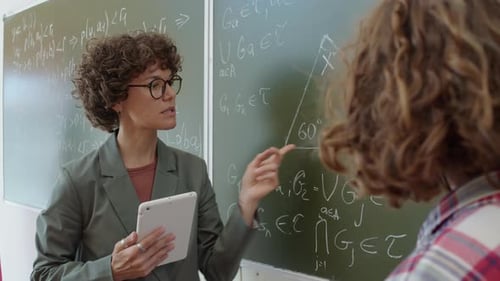 Dedicated Teacher Explaining Math on Chalkboard to Student
