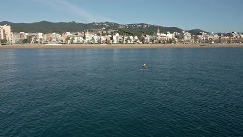 Orbits over a solo stand-up paddle surf with a view of the town in the background, on a sunny autumn