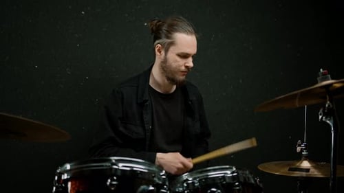 un joven baterista masculino toca una batería en un estudio de grabación en el ensayo de un músico profesional