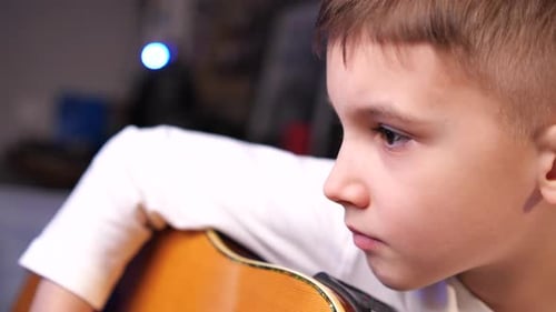 Closeup Boy aprende a tocar la guitarra usando cursos en línea en su aplicación de teléfono