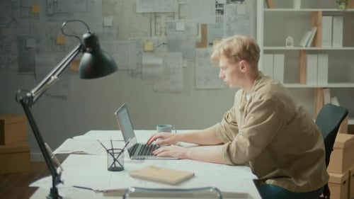 Vue latérale Jeune manager motivé travaillant sur un ordinateur portable dans un bureau moderne
