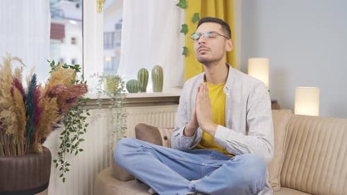 Young Adult Meditating Peacefully on Couch at Home
