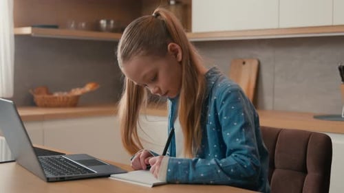 Cute Primary Caucasian School Girl Studying at Kitchen with Laptop