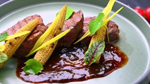 Chef serves beef with sauce and garnishes on a green plate.
