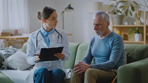 Caring Doctor Consulting Senior Man on Couch