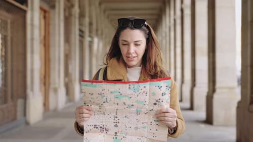 Woman Smiling While Reading Map in City Walkway