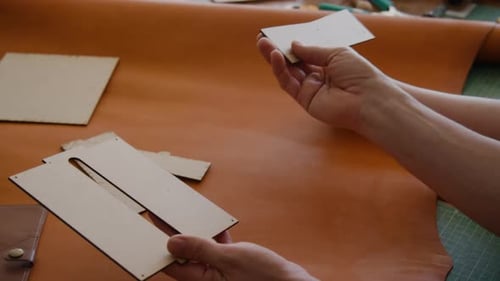 Unrecognizable Colleagues Examining Patterns for Cutting Hide at Workshop Table
