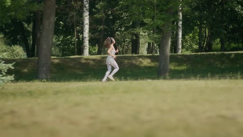 Athletic Woman Running in Park with Lush Green Trees