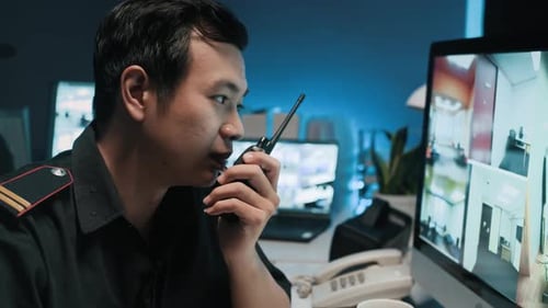 Security Guard Working in Dark Surveillance Room