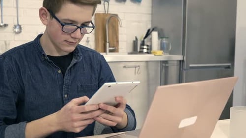 Teen Uses Tablet and Laptop in Kitchen