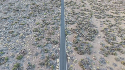 Aerial view over a barren landscape in Tenerife with a solitary road cutting through.