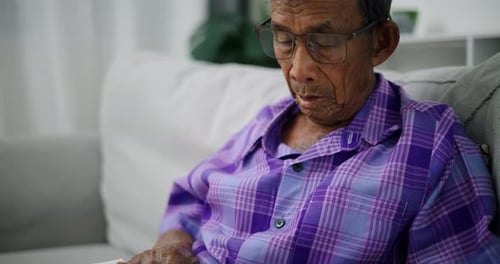 Senior man reading book while relaxing on sofa