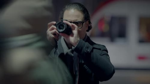 Man Taking Pictures on a City Street at Night