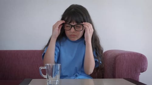 Girl Holds Glasses at a Table Indoors