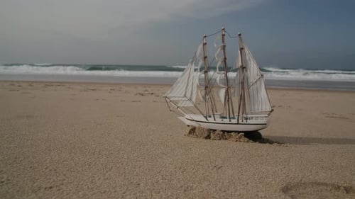 A tiny sailboat sits on a sandy beach, surrounded by gentle waves. Perfect for travel, vacation, and