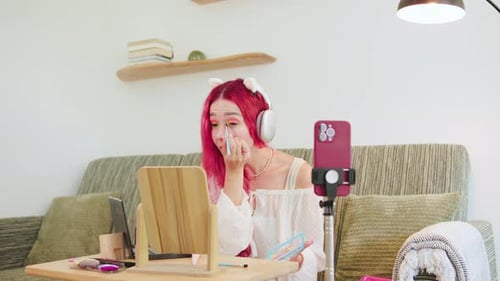 Woman with pink hair doing makeup tutorial